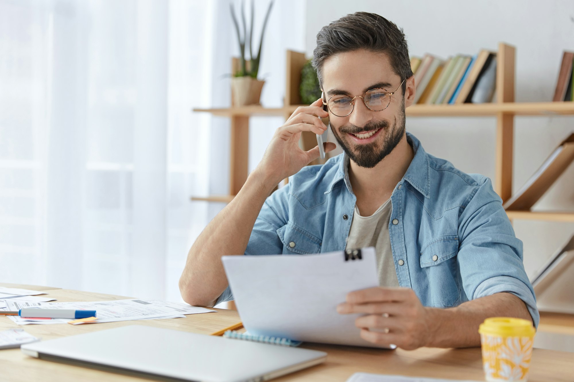 Happy young unexperienced male prepares business report, asks advice or consultancy in professional